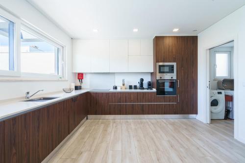 a kitchen with white and wood cabinets and a sink at Villa Mauricio with jacuzzi and private swimming pool in Mariquiteira