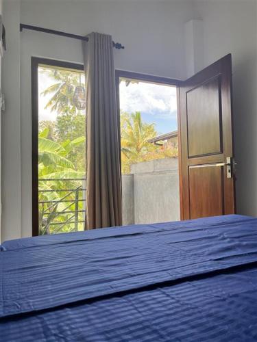 a bedroom with a blue bed and a window at Melon Guest - Weligama in Weligama