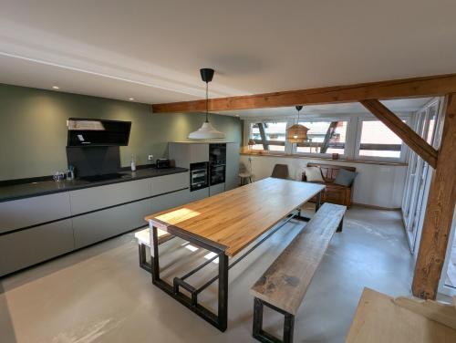 una cucina con un tavolo di legno in una stanza di L'Étable - à l'Ancienne Ferme 