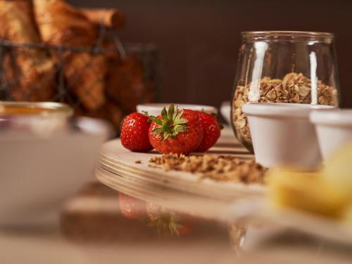 a table with strawberries and a jar of granola at A-ROSA Kurhaus Binz in Binz