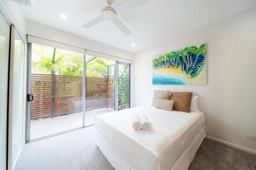 una camera da letto con un letto bianco e una grande finestra di Doorilla Coastal Retreat a Mission Beach