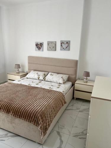 a white bedroom with a bed and two night stands at Apartment Elis in Kamëz