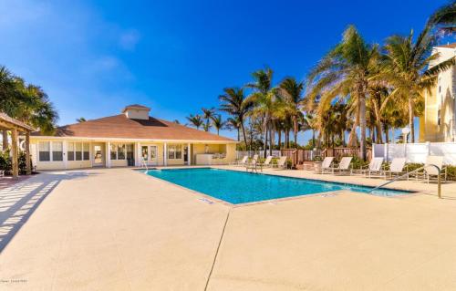 a swimming pool in front of a house with palm trees at Tranquil Condo Walk to Beach in Melbourne