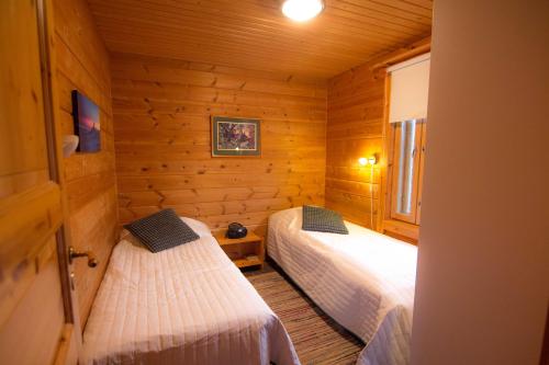 a bedroom with two beds in a log cabin at Saivaara Cottages in Kilpisjärvi