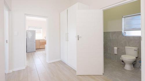 a white bathroom with a toilet and a refrigerator at Ondermaat in Agulhas