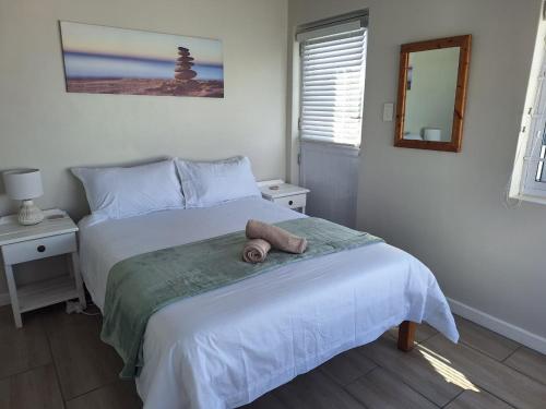 a bedroom with a bed with a teddy bear on it at Ondermaat in Agulhas