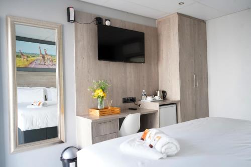 a bedroom with a mirror and a bed and a desk at Khayalami Hotel - Secunda in Secunda