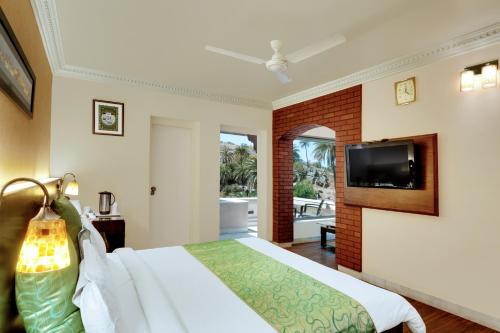 a bedroom with a bed and a flat screen tv at Chacha Inn The Garden Retreat in Mount Ābu