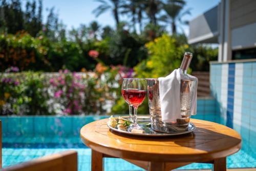 a glass of wine on a table next to a pool at Constantinou Bros Asimina Suites Hotel in Paphos City