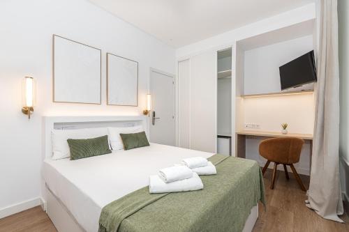 a white bedroom with a large bed and a chair at Queens Bernabéu in Madrid