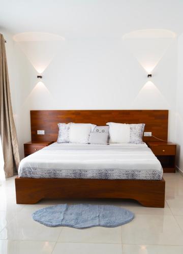 a bedroom with a large bed with a wooden headboard at EMY guest HOUSE in Kofa