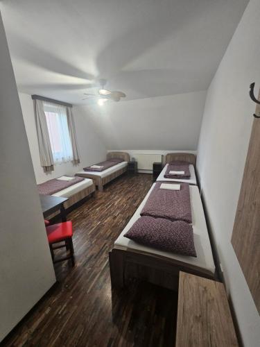 a room with three beds and a table and chairs at Régi Csárda és Panzió in Magyarszerdahely