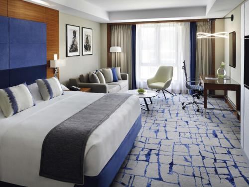 a hotel room with a large bed and a living room at Mövenpick Hotel & Apartments Bur Dubai in Dubai