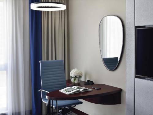 a room with a desk with a chair and a mirror at Mövenpick Hotel & Apartments Bur Dubai in Dubai
