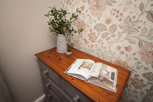 a wooden dresser with a book and a plant on it at Charming 3-Bedroom Home Close to Attractions in Lincoln