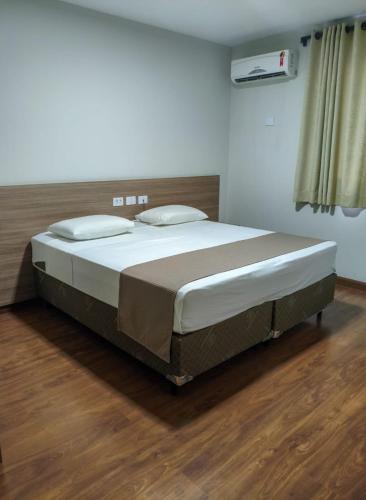 a large bed in a bedroom with a wooden floor at Arca's Hotel Umuarama in Umuarama