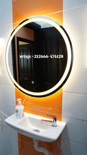 a bathroom sink with a round mirror on the wall at Hassan host Housse in Er Rachidia