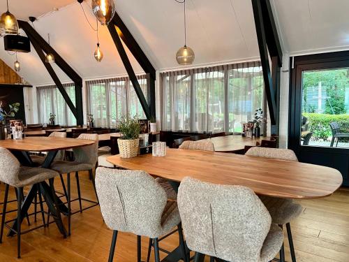 a restaurant with wooden tables and chairs and windows at Vakantiepark de Luttenberg in Luttenberg