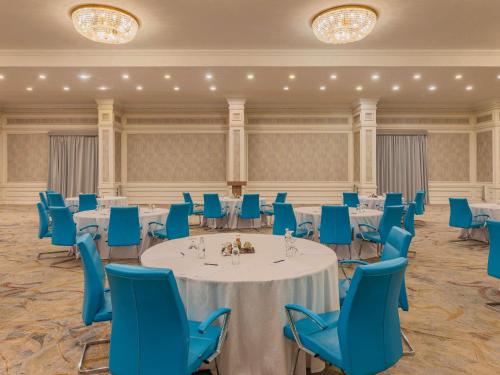 a banquet hall with tables and blue chairs at Mövenpick Hotel Cairo - Media City in 6th Of October