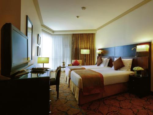 a hotel room with two beds and a flat screen tv at Movenpick Makkah Hajar Tower in Makkah