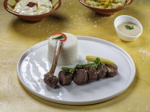 a white plate with some food on a table at Movenpick Makkah Hajar Tower in Makkah