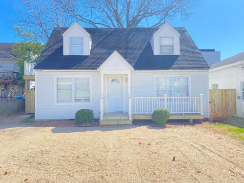 a white house with a porch with a blue door at 508 A The Shore Break Cottage in Virginia Beach