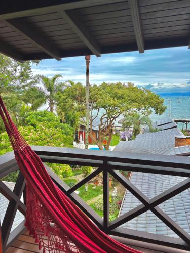 a hammock on a balcony with a view of the ocean at Pousada Mar de Dentro in Florianópolis