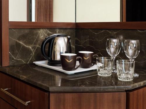 a counter with a tea kettle and glasses on it at Mövenpick Hotel Karachi in Karachi