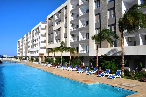a swimming pool with lounge chairs and a hotel at Fanadir Luxury Suites All Inclusive in Hurghada