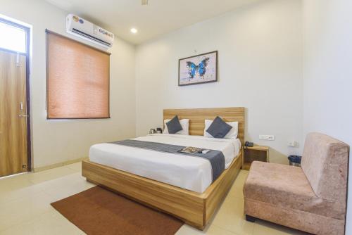 a bedroom with a bed and a chair at HOTEL OXUS, Pratap Nagar in Jaipur