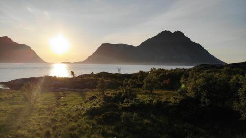 a sunset over the water with mountains in the background at Serene cabin in Lofoten with sauna in Kleppstad