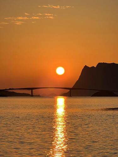 a sunset over the water with a bridge in the background at Serene cabin in Lofoten with sauna in Kleppstad