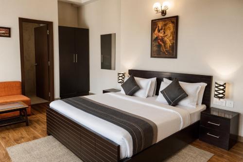 a bedroom with a large bed and a chair at The Amber Signature Vrindavan # A Contemporary Luxury Hotel With #Lift# Parking# Ac Rooms# & Elegant interior # Near Prem Mandir in Vrindāvan