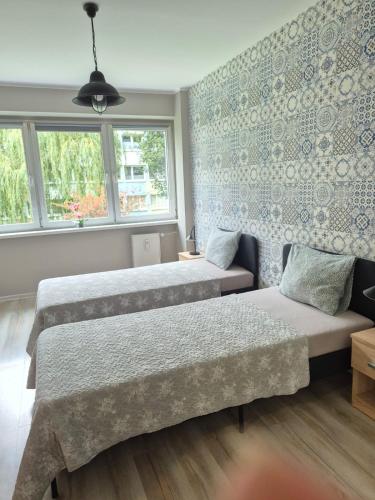 a bedroom with two beds and a couch and windows at JDK Apartamenty Serbinowska 53m2 6-osobowy in Kalisz