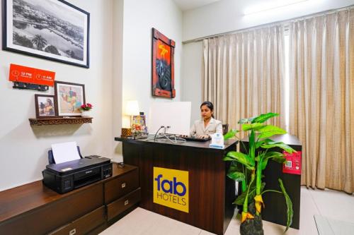 eine Frau sitzt an einem Rezeptionstresen in einem Hotelzimmer in der Unterkunft FabHotel Mumbai Corporate Apartments Bandra in Mumbai