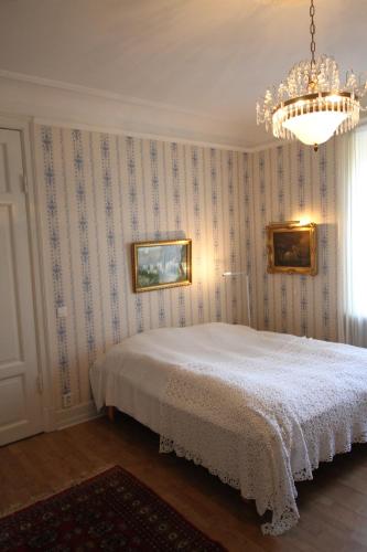 a bedroom with a white bed and a chandelier at Gästlägenhet in Sövde