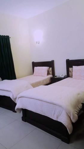 two beds sitting next to each other in a room at Hotel Inn in Karachi