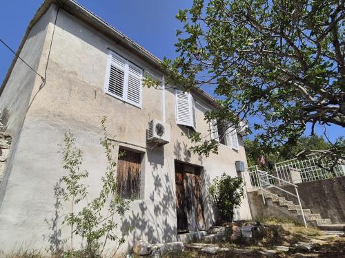an old white building with windows and a staircase at Apartmani Aurelia in Veliki Drvenik