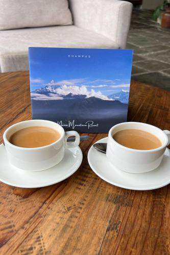 two cups of coffee on a table with a book at Nana Mountain Resort Mt Annapurna View in Astam