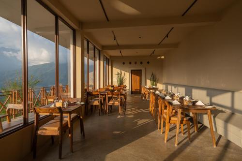 a restaurant with tables and chairs and large windows at Nana Mountain Resort Mt Annapurna View in Astam