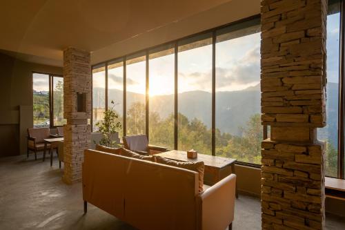 a living room with a couch and a large window at Nana Mountain Resort Mt Annapurna View in Astam