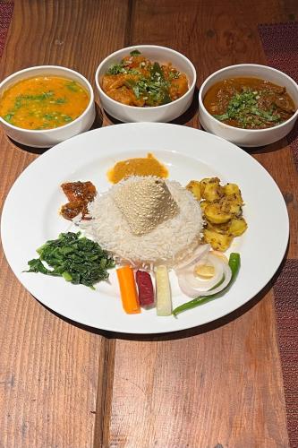 a plate of food on a table with bowls of food at Nana Mountain Resort Mt Annapurna View in Astam