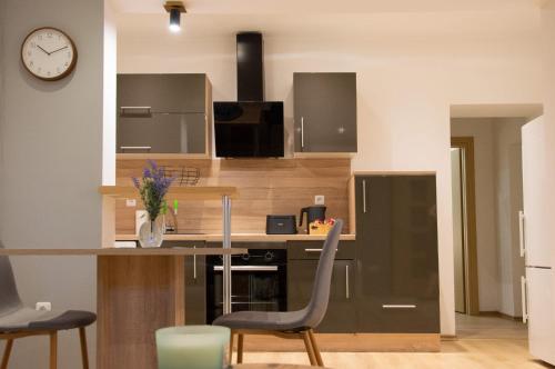 a kitchen with a counter with chairs and a clock at Apartman Nora in Široki Brijeg