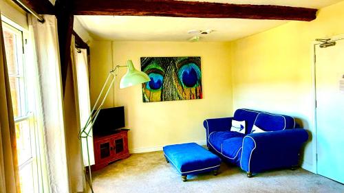 a living room with a blue chair and a tv at The Bull Inn in Little Walsingham