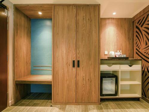 a kitchen with wooden cabinets and a built in microwave at Mercure Langkawi Pantai Cenang in Pantai Cenang