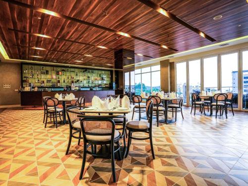 a dining room with tables and chairs and windows at Mercure Langkawi Pantai Cenang in Pantai Cenang