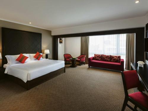 a hotel room with a bed and a red couch at Movenpick Suriwongse Hotel Chiang Mai in Chiang Mai