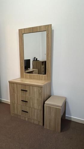 a wooden dresser with a mirror and a stool at Khalifa A Home Stay Small Room in Sabkhah