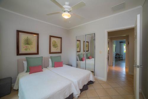 a bedroom with a white bed with pink and green pillows at Del Mar 4N 3 bdr Garden View in Los Suenos in Herradura