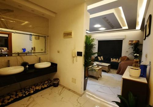 a bathroom with two sinks and a living room at Modern Apartment in Amman in Amman